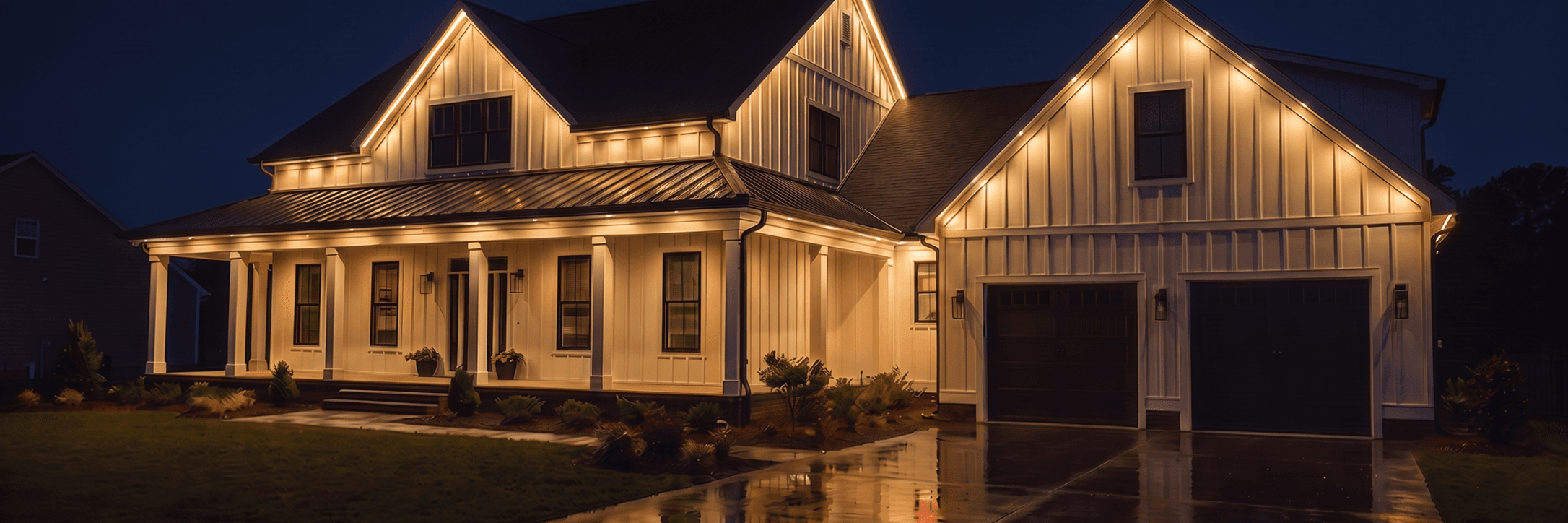 Traditional siding house viewed closely from the driveway at night, with warm white roofline lighting